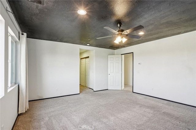 unfurnished room featuring visible vents, light colored carpet, ceiling fan, and a textured ceiling