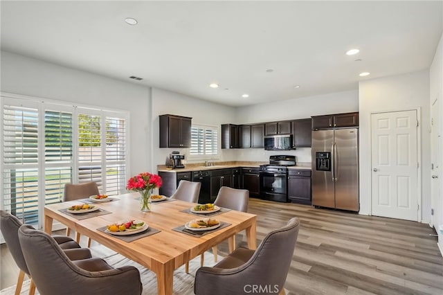 kitchen with light wood-type flooring, black appliances, recessed lighting, dark brown cabinetry, and light countertops