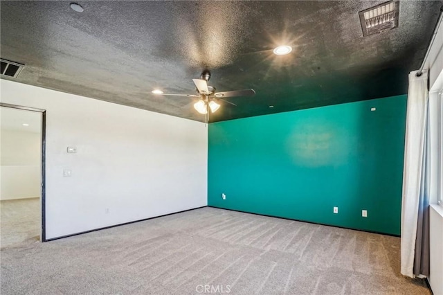 unfurnished room with visible vents, carpet floors, and a textured ceiling