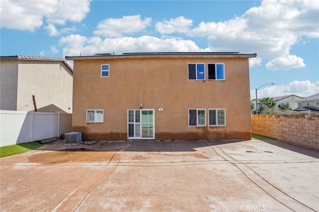 rear view of property featuring a patio, central AC unit, a fenced backyard, and stucco siding