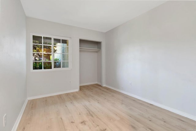 unfurnished bedroom featuring wood finished floors, baseboards, and a closet