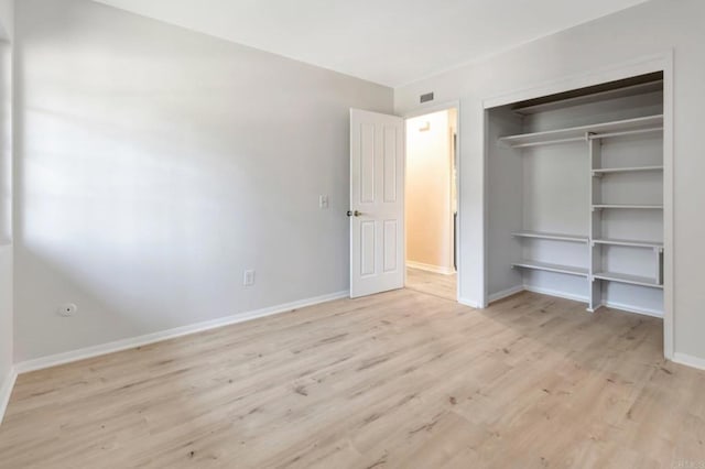 unfurnished bedroom featuring a closet, light wood-style flooring, and baseboards