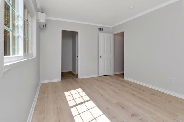 unfurnished bedroom featuring crown molding, light wood-style flooring, baseboards, and a wall mounted AC