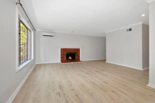 unfurnished living room with visible vents, light wood-style flooring, a wall mounted AC, crown molding, and baseboards