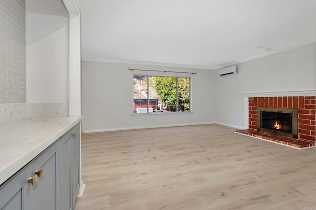 unfurnished living room with baseboards, a wall mounted AC, ornamental molding, light wood-style floors, and a brick fireplace