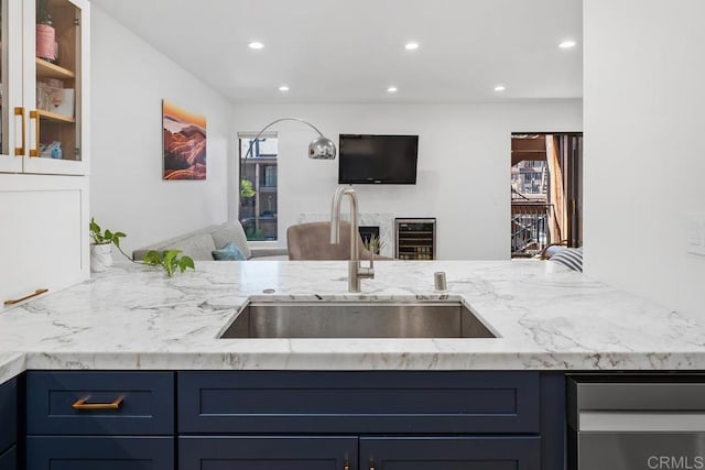 kitchen featuring light stone counters, blue cabinetry, recessed lighting, a sink, and open floor plan