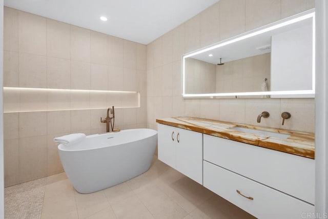 bathroom with vanity, tile walls, a soaking tub, and recessed lighting