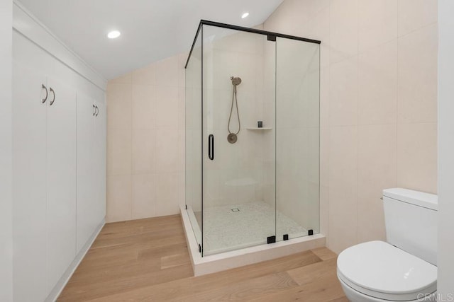 full bath featuring toilet, wood finished floors, and a shower stall