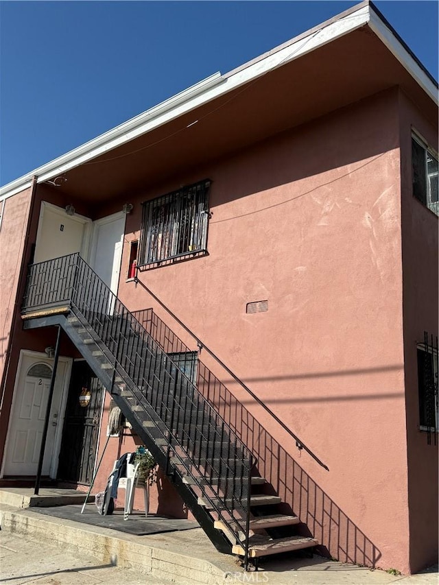 view of side of home featuring stairs and stucco siding