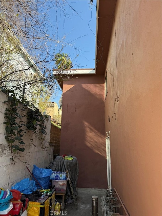 view of side of home with stucco siding and fence