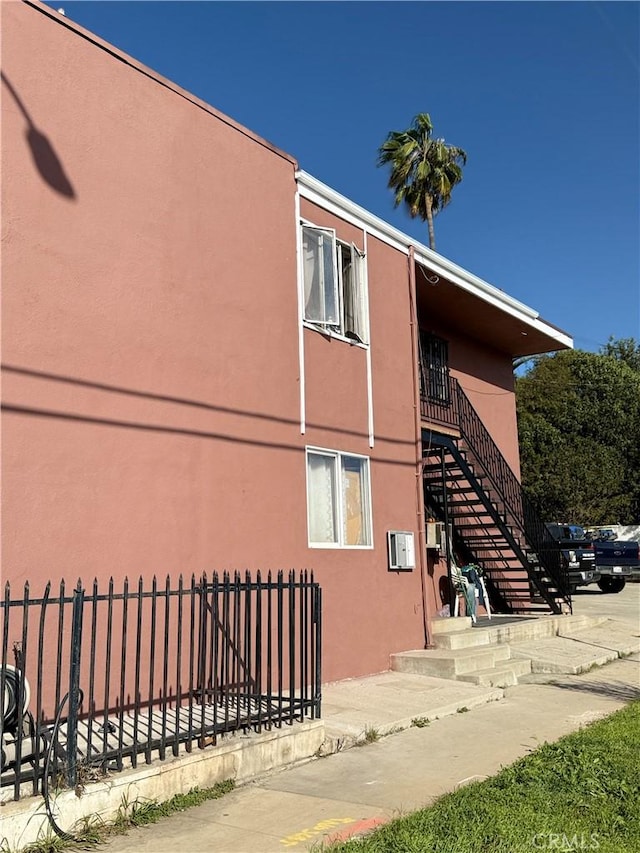 view of building exterior with stairway and fence