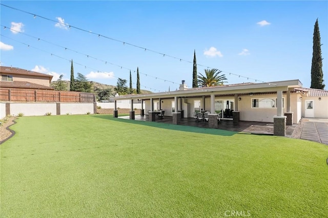 rear view of house with a yard, a patio area, fence, and stucco siding