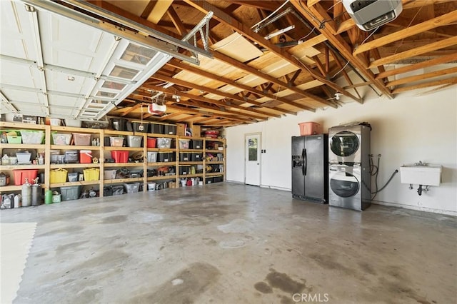 garage featuring a sink, black fridge with ice dispenser, a garage door opener, and stacked washer and dryer