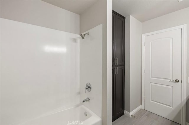 bathroom with shower / bathing tub combination, baseboards, and wood finished floors