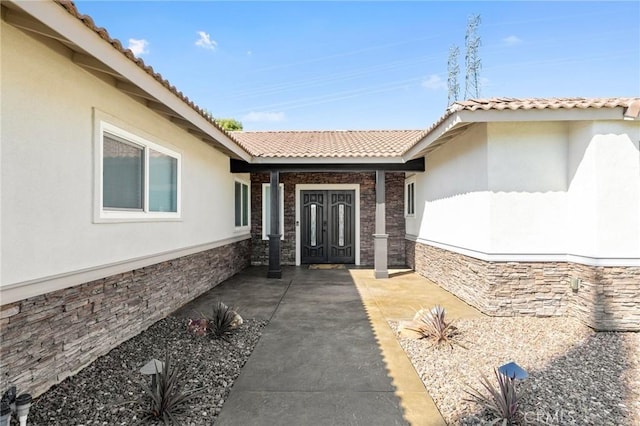 property entrance featuring stucco siding and a tile roof