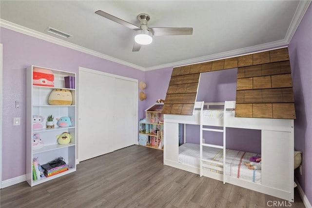 unfurnished bedroom with visible vents, crown molding, a ceiling fan, and wood finished floors