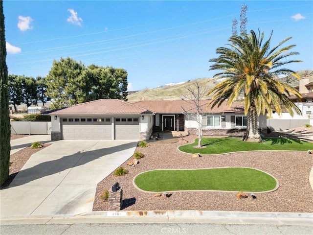 ranch-style home with stucco siding, stone siding, concrete driveway, an attached garage, and a tiled roof