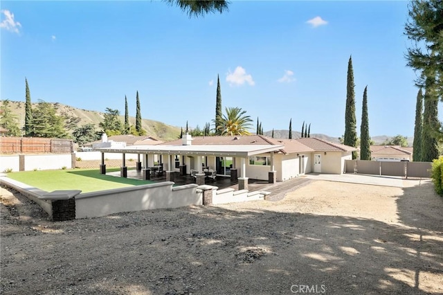 rear view of house with a mountain view, a patio area, and fence