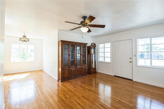 entrance foyer featuring ceiling fan with notable chandelier, wood finished floors, and baseboards