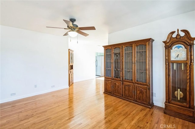 empty room featuring light wood-type flooring, baseboards, and ceiling fan