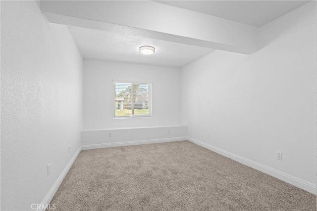 carpeted spare room featuring baseboards