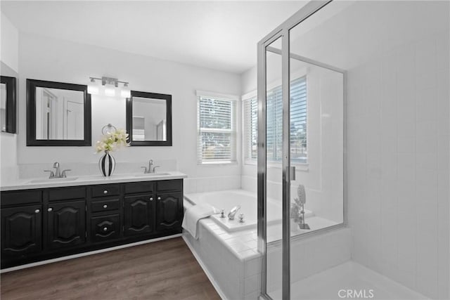 full bath featuring a sink, wood finished floors, a bath, and double vanity