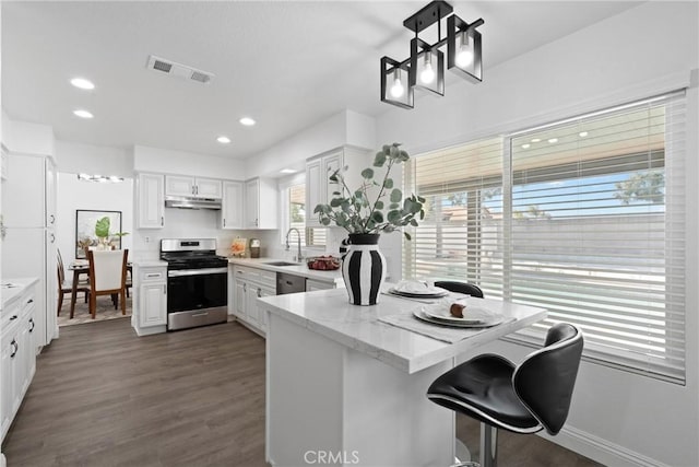 kitchen with visible vents, a peninsula, a sink, under cabinet range hood, and stainless steel gas range oven