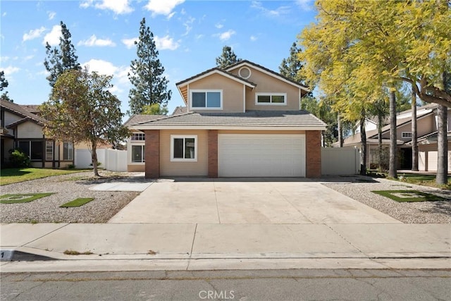 traditional-style home with brick siding, an attached garage, concrete driveway, and fence