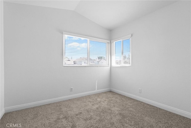 carpeted spare room featuring baseboards and lofted ceiling