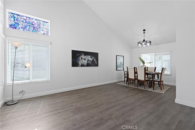 dining area with an inviting chandelier, wood finished floors, baseboards, and high vaulted ceiling