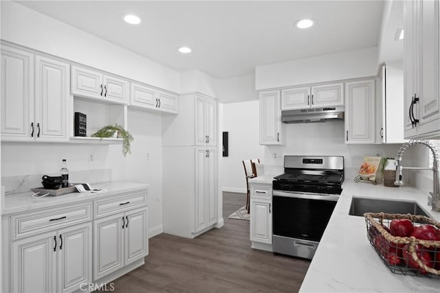 kitchen featuring light stone countertops, under cabinet range hood, wood finished floors, white cabinets, and gas stove