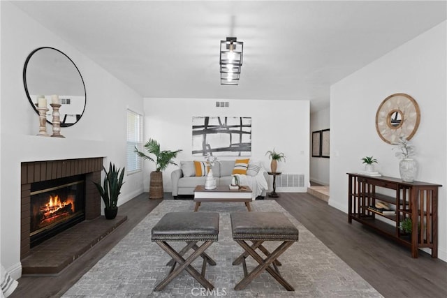 living area featuring a fireplace, wood finished floors, visible vents, and baseboards