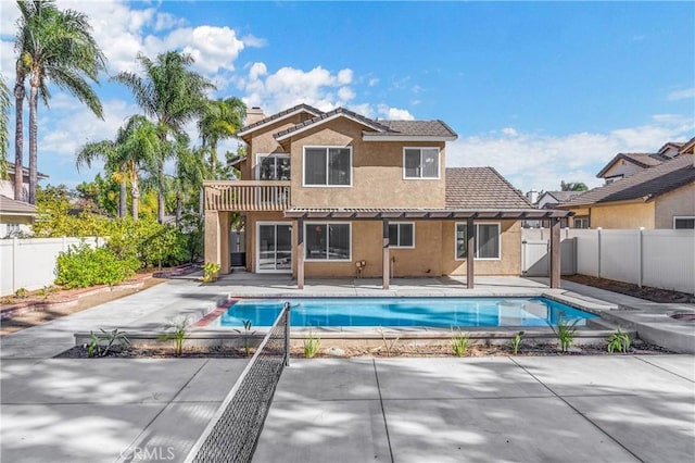 rear view of property featuring stucco siding, a fenced backyard, a fenced in pool, a chimney, and a patio area