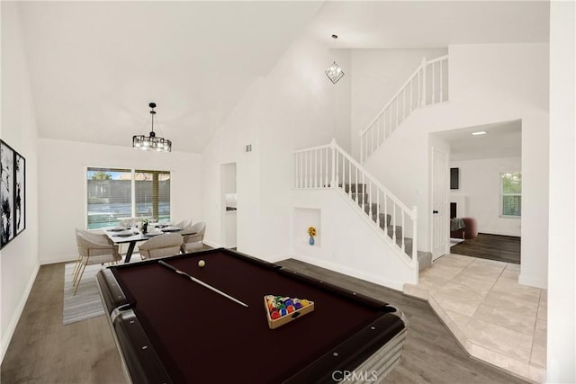 playroom with high vaulted ceiling, wood finished floors, baseboards, and a chandelier