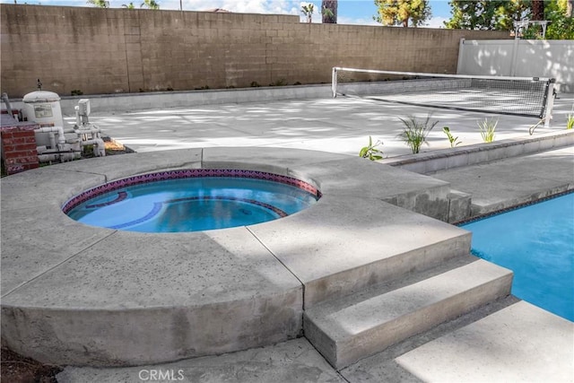 view of pool featuring an in ground hot tub and fence