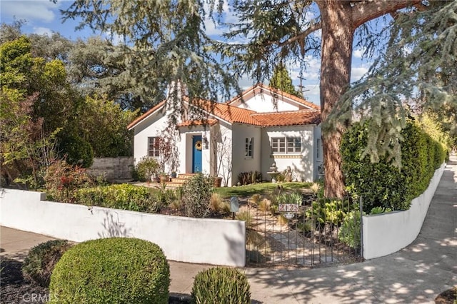 mediterranean / spanish home featuring a fenced front yard, stucco siding, and a tile roof