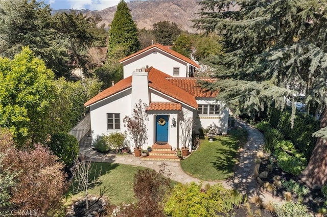 mediterranean / spanish home featuring a tile roof, a mountain view, a front yard, and stucco siding