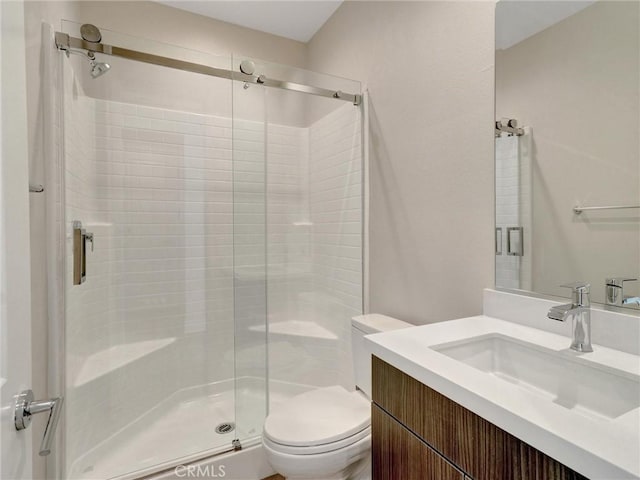 bathroom with toilet, a stall shower, and vanity