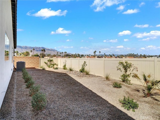 view of yard featuring a fenced backyard, a mountain view, and central AC