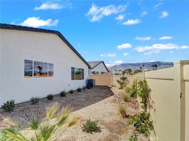 view of yard featuring a mountain view, central AC, and fence