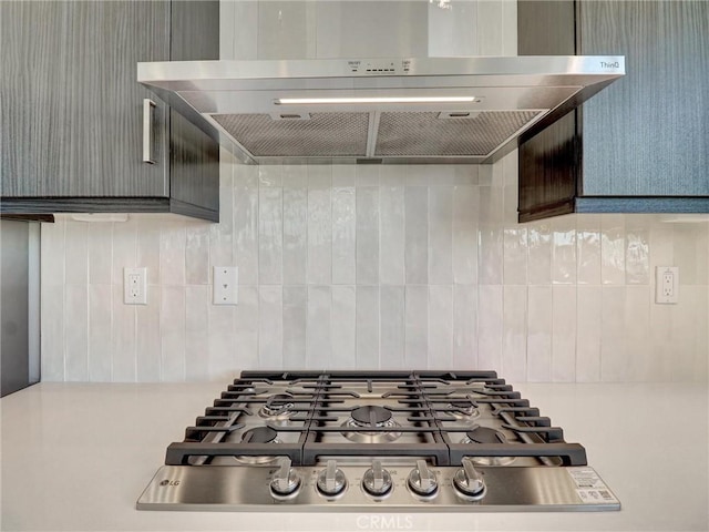 interior details with decorative backsplash, wall chimney exhaust hood, and stainless steel gas cooktop