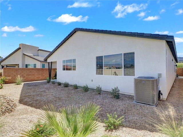 view of side of home with central air condition unit, fence, and stucco siding