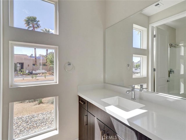 bathroom featuring vanity, a shower, and visible vents