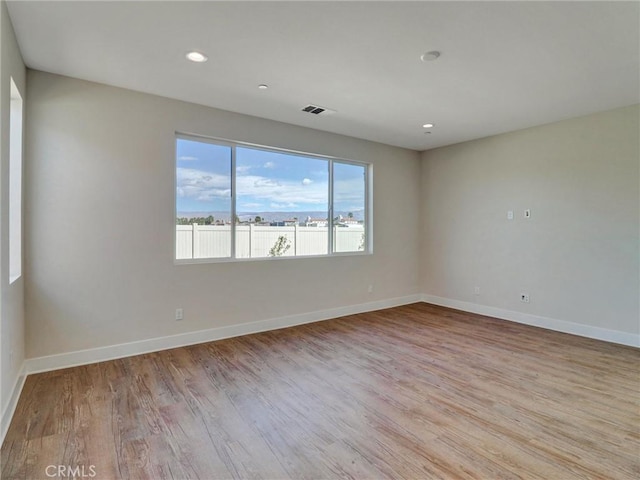 empty room with recessed lighting, visible vents, light wood-type flooring, and baseboards