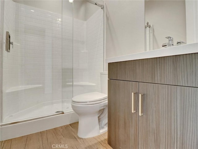 bathroom featuring a shower stall, toilet, and wood finished floors