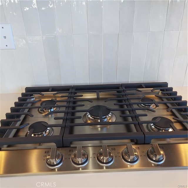 interior details with range, tasteful backsplash, and stainless steel gas cooktop