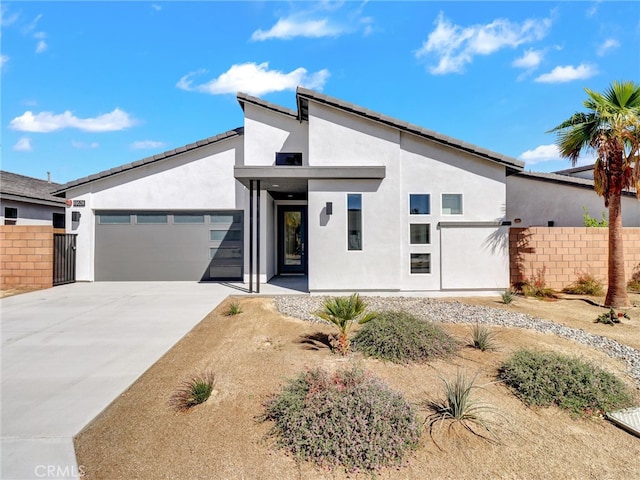 view of front facade with fence, a garage, driveway, and stucco siding