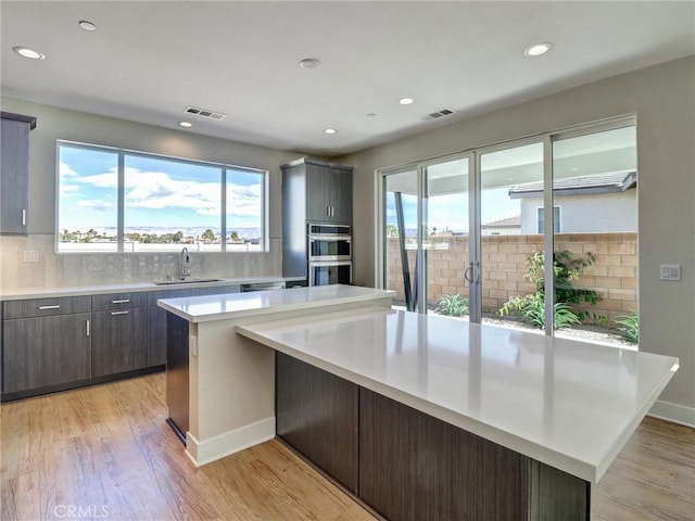 kitchen featuring light countertops, visible vents, stainless steel double oven, and a sink