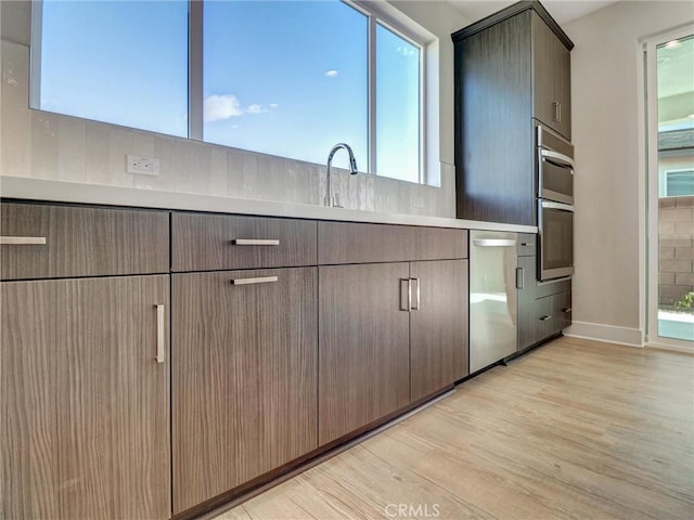 kitchen with light countertops, light wood-style flooring, appliances with stainless steel finishes, and a sink