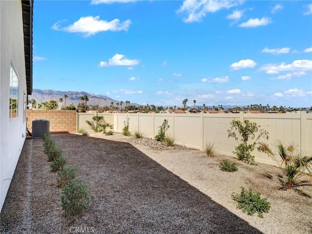 view of yard with a fenced backyard, a mountain view, and central AC